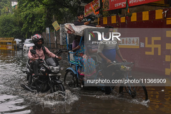 People are wading through a flooded street after heavy rains in New Delhi, India, on June 28, 2024. 