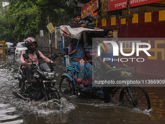 People are wading through a flooded street after heavy rains in New Delhi, India, on June 28, 2024. (