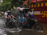 People are wading through a flooded street after heavy rains in New Delhi, India, on June 28, 2024. (