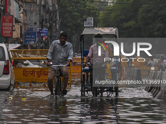 People are wading through a flooded street after heavy rains in New Delhi, India, on June 28, 2024. (