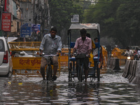 People are wading through a flooded street after heavy rains in New Delhi, India, on June 28, 2024. (