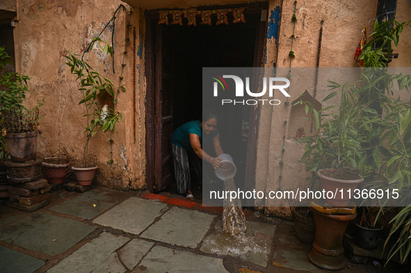 Unnati Prakash, 42, is throwing water with the help of a bucket outside her house that is flooded with water after heavy rains in New Delhi,...