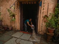 Unnati Prakash, 42, is throwing water with the help of a bucket outside her house that is flooded with water after heavy rains in New Delhi,...