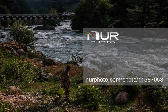 A BSF soldier is carrying an empty can as he walks towards the River Lidder to fill it in Pahalgam, Jammu and Kashmir, India, on June 28, 20...