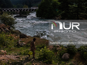 A BSF soldier is carrying an empty can as he walks towards the River Lidder to fill it in Pahalgam, Jammu and Kashmir, India, on June 28, 20...