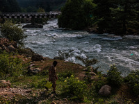 A BSF soldier is carrying an empty can as he walks towards the River Lidder to fill it in Pahalgam, Jammu and Kashmir, India, on June 28, 20...