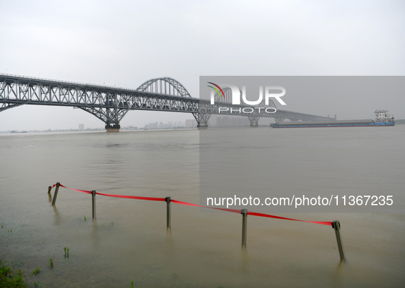 Ships are sailing past the Jiujiang Yangtze River Bridge with high water levels, most of the piers submerged by river water, in Jiujiang, Ch...