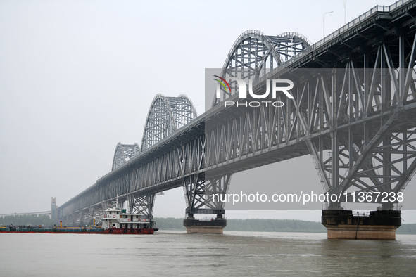 Ships are sailing past the Jiujiang Yangtze River Bridge with high water levels, most of the piers submerged by river water, in Jiujiang, Ch...