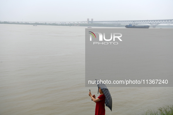 Citizens are taking photos along the Yangtze River in Jiujiang city, Jiangxi province, China, on June 28, 2024. The water level at Jiujiang...