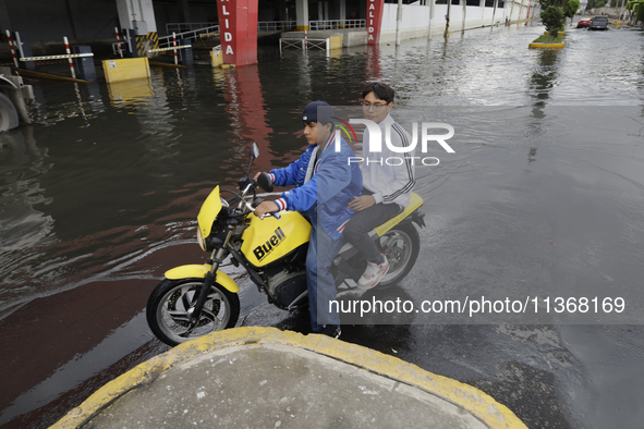 Young people are trying to pass on motorbikes outside a flooded shopping mall in Ecatepec, State of Mexico, due to the rains during the last...