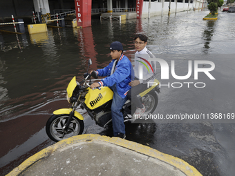 Young people are trying to pass on motorbikes outside a flooded shopping mall in Ecatepec, State of Mexico, due to the rains during the last...