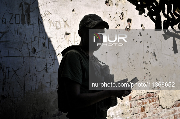 An aerial reconnaissance man of the 148th separate artillery brigade of the Ukrainian Air Assault Forces is standing against a wall riddled...