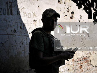 An aerial reconnaissance man of the 148th separate artillery brigade of the Ukrainian Air Assault Forces is standing against a wall riddled...