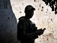 An aerial reconnaissance man of the 148th separate artillery brigade of the Ukrainian Air Assault Forces is standing against a wall riddled...