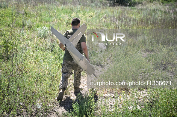 An aerial reconnaissance man of the 148th separate artillery brigade of the Ukrainian Air Assault Forces is carrying a disassembled drone to...