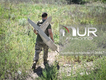 An aerial reconnaissance man of the 148th separate artillery brigade of the Ukrainian Air Assault Forces is carrying a disassembled drone to...