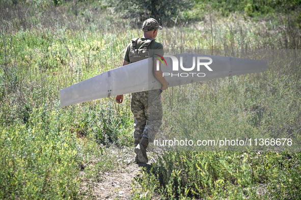 An aerial reconnaissance man of the 148th separate artillery brigade of the Ukrainian Air Assault Forces is carrying a disassembled drone to...