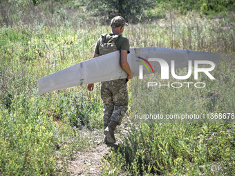 An aerial reconnaissance man of the 148th separate artillery brigade of the Ukrainian Air Assault Forces is carrying a disassembled drone to...