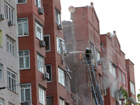 A firefighter in an aerial work platform is putting out a fire during a search and rescue effort at the apartment block hit by the Russian m...