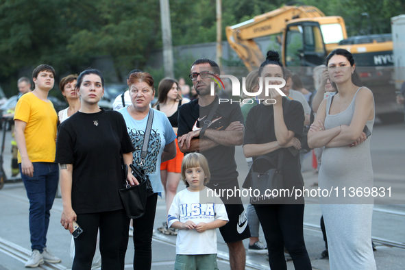 Onlookers are watching a search and rescue effort at an apartment block hit by a Russian missile in Dnipro, Ukraine, on June 28, 2024. Russi...