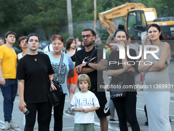 Onlookers are watching a search and rescue effort at an apartment block hit by a Russian missile in Dnipro, Ukraine, on June 28, 2024. Russi...