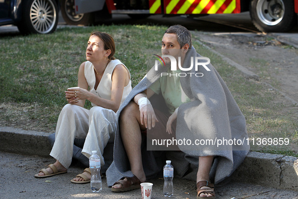 People affected by the June 28 Russian missile attack on the apartment block are sitting on the curb in Dnipro, Ukraine, on June 29, 2024. R...