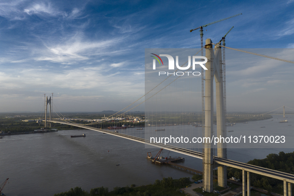 An aerial photo is showing ships passing under the Xianxin Road Yangtze River Bridge under construction in Nanjing, China, on June 29, 2024....