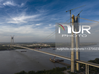 An aerial photo is showing ships passing under the Xianxin Road Yangtze River Bridge under construction in Nanjing, China, on June 29, 2024....