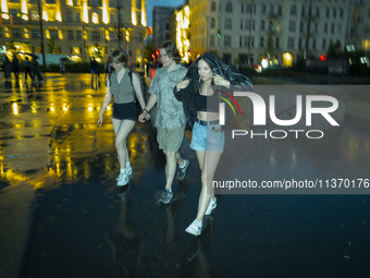 Young people are seen walking during a downpour in Warsaw, Poland on 28 June, 2024. (