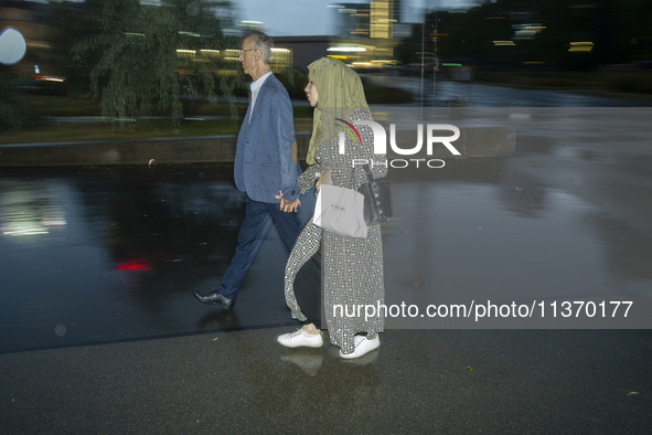 A man and a woman with a hedscarf are seen holding hands in Warsaw, Poland on 28 June, 2024. 