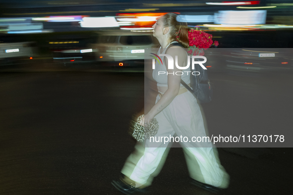 A woman with a bouquet of flowers in her backpack is seen during a downpour in Warsaw, Poland on 28 June, 2024. 