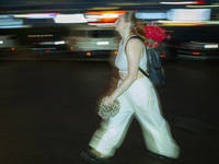 A woman with a bouquet of flowers in her backpack is seen during a downpour in Warsaw, Poland on 28 June, 2024. (