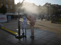 Tow women wearing headscarfs, hijabs are seen cooling off at a misting station in Warsaw, Poland on 28 June, 2024. (