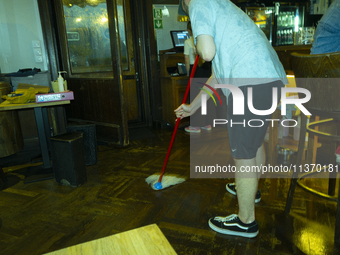 A man is seen sweeping a floor in a restaurant after a downpour in Warsaw, Poland on 28 June, 2024. (