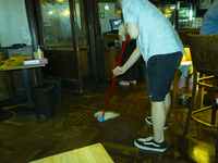 A man is seen sweeping a floor in a restaurant after a downpour in Warsaw, Poland on 28 June, 2024. (