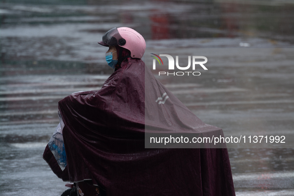 A woman is riding a motor scooter in stormy weather in Shanghai, China, on June 30, 2024. 