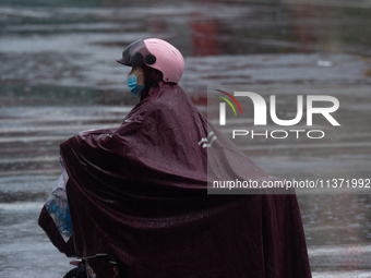 A woman is riding a motor scooter in stormy weather in Shanghai, China, on June 30, 2024. (