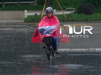 A woman is riding a motor scooter in stormy weather in Shanghai, China, on June 30, 2024. (