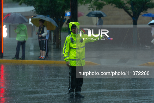 A traffic police officer is directing traffic in stormy weather in Shanghai, China, on June 30, 2024. 