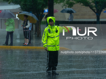 A traffic police officer is directing traffic in stormy weather in Shanghai, China, on June 30, 2024. (