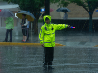 A traffic police officer is directing traffic in stormy weather in Shanghai, China, on June 30, 2024. (