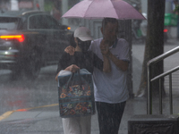 A couple is struggling with an umbrella in stormy weather in Shanghai, China, on June 30, 2024. (