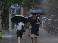 People are walking with umbrellas under heavy rain in stormy weather in Shanghai, China, on June 30, 2024. (