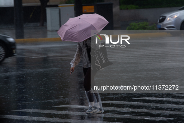 A woman is walking with an umbrella in stormy weather in Shanghai, China, on June 30, 2024. 