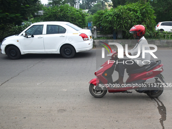 A person is riding an electric scooter in Kolkata, India, on June 30, 2024. (