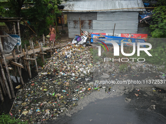 A person is passing a canal full of plastic waste on the outskirts of Kolkata, India, on June 30, 2024. (