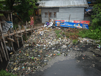 A person is passing a canal full of plastic waste on the outskirts of Kolkata, India, on June 30, 2024. (