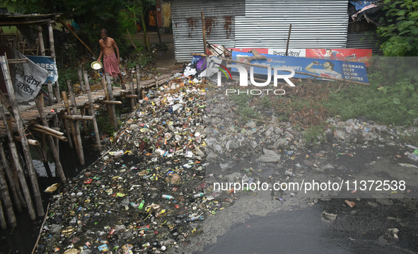 A person is passing a canal full of plastic waste on the outskirts of Kolkata, India, on June 30, 2024. 