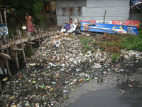 A person is passing a canal full of plastic waste on the outskirts of Kolkata, India, on June 30, 2024. (