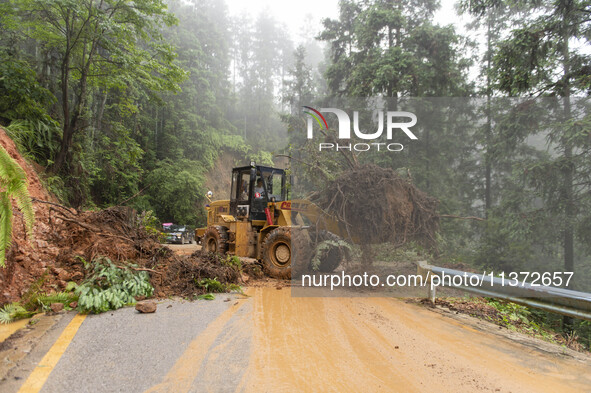 Workers are driving machinery to clear a collapsed road section at Bingmei Street in Congjiang county, Southwest China's Guizhou province, i...